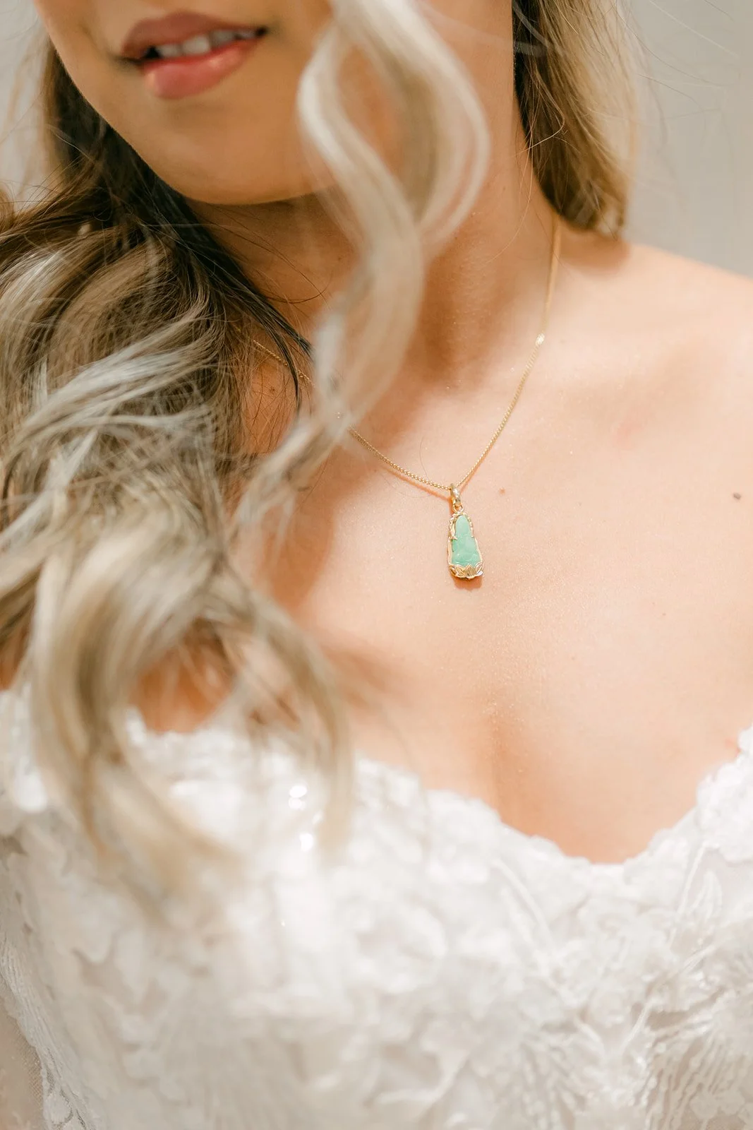 Close up of the bride's jade pendant necklace and soft curls