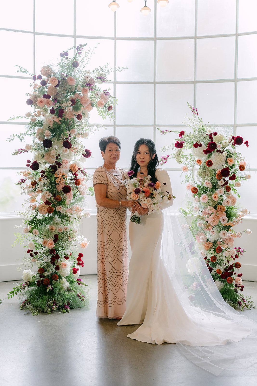 Denise with her mom between the floral columns.