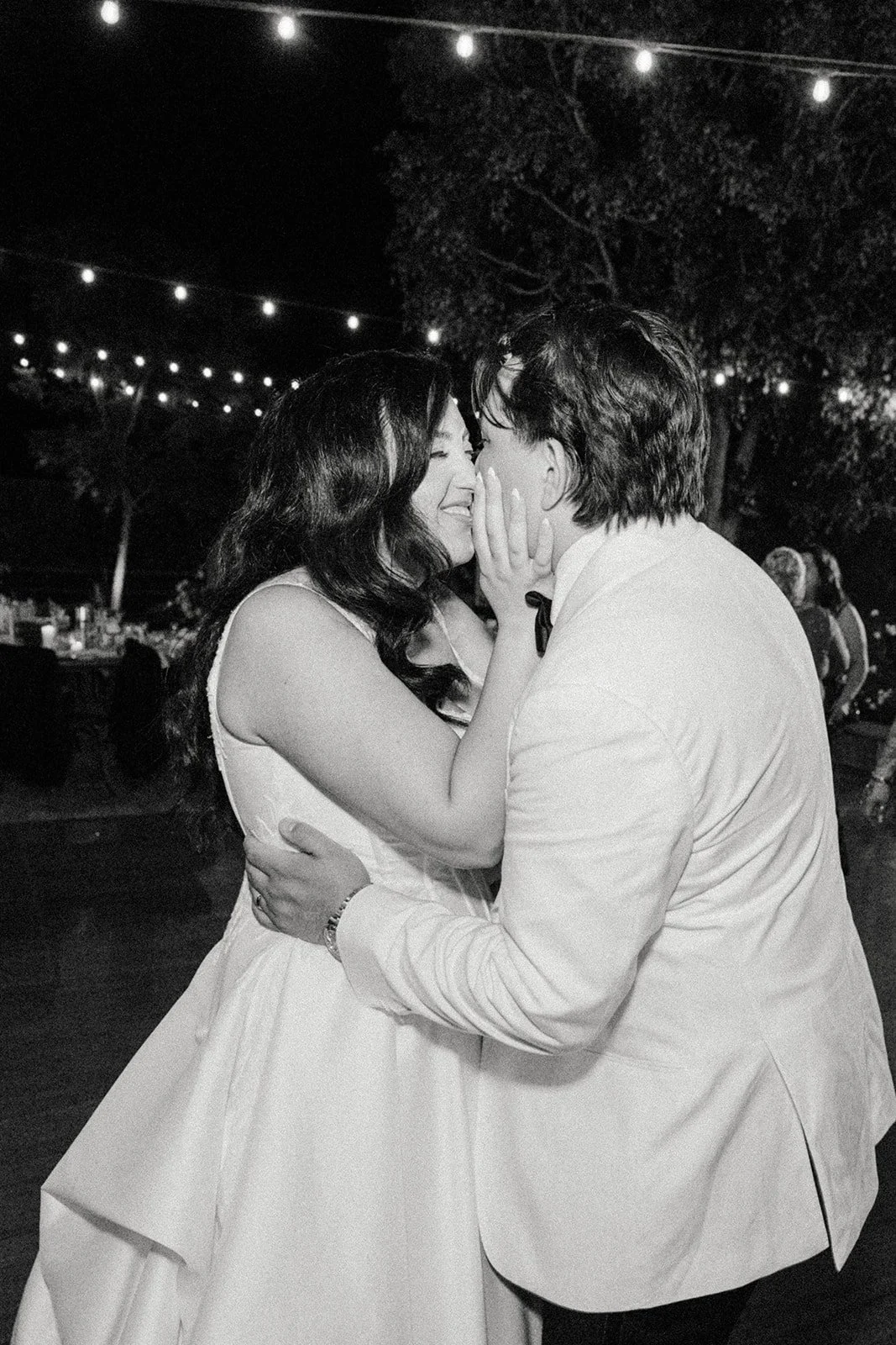 Black and white photo of the bride kissing the groom on the cheek