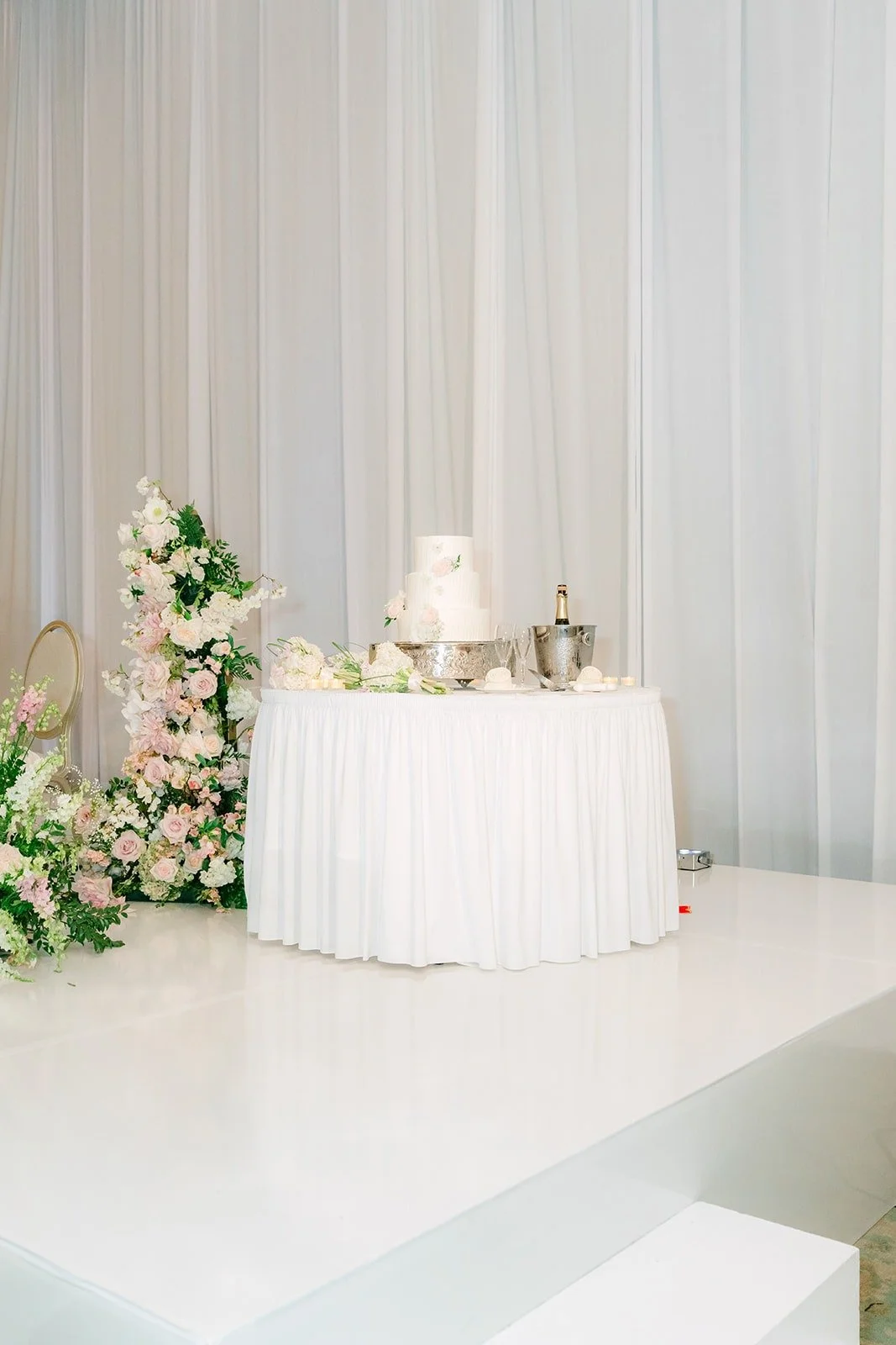 The three tier white cake on the stage in the San Gabriel Ballroom