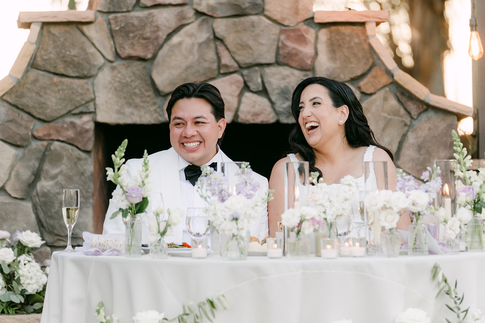 Newlyweds laughing during speeches at the sweetheart table