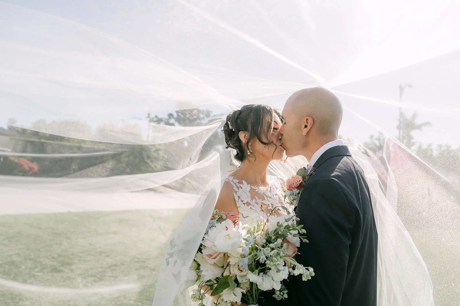 Francesca and Daniel kiss under her veil on the lawn at The Westin Anaheim Resort