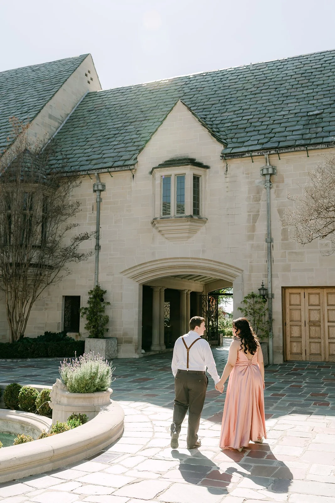 Saira and Matthew walking across the cobblestone motor court toward the mansion entrance.