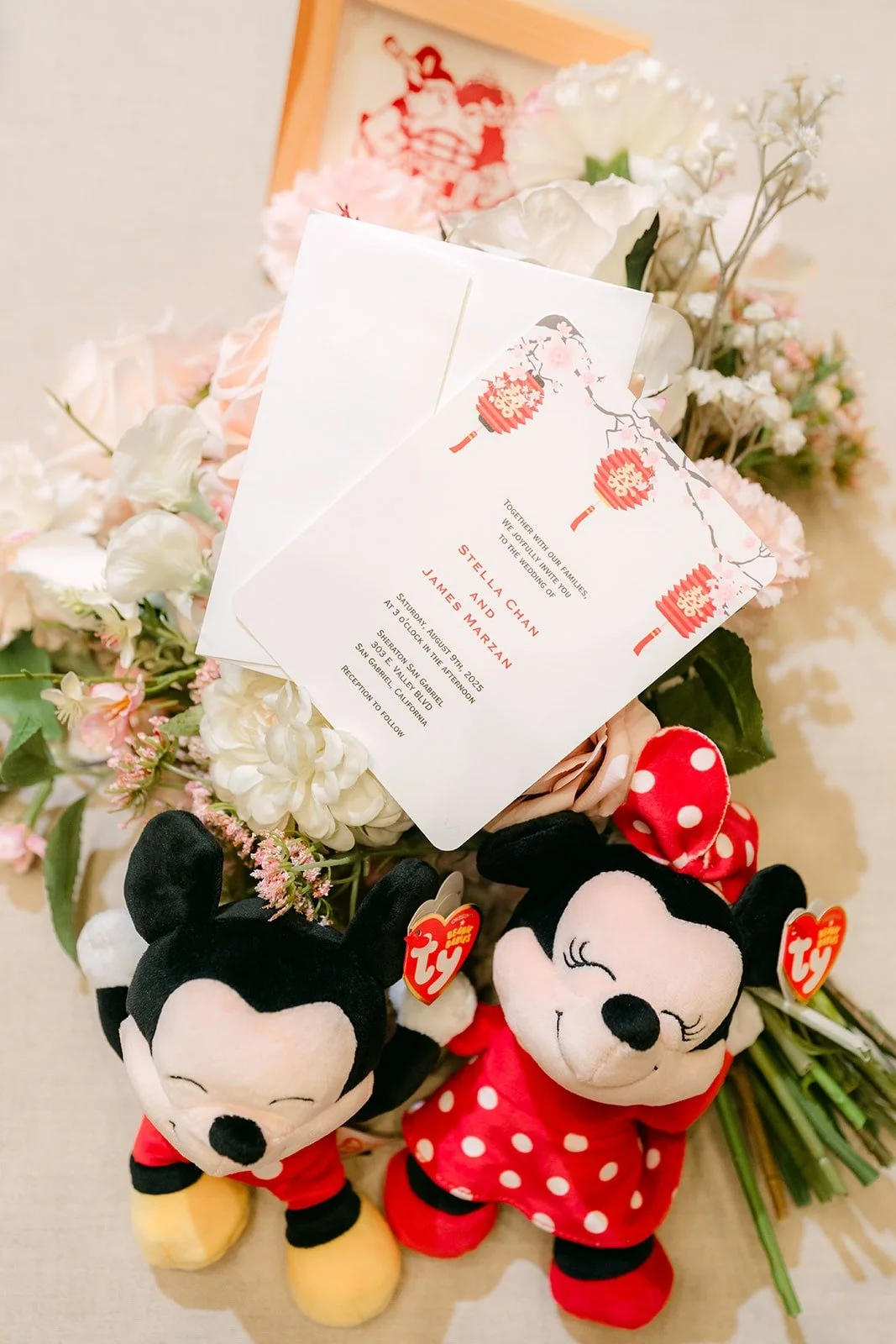 Stella and James's red and white wedding invitations styled with Mickey and Minnie plush toys and blush flowers