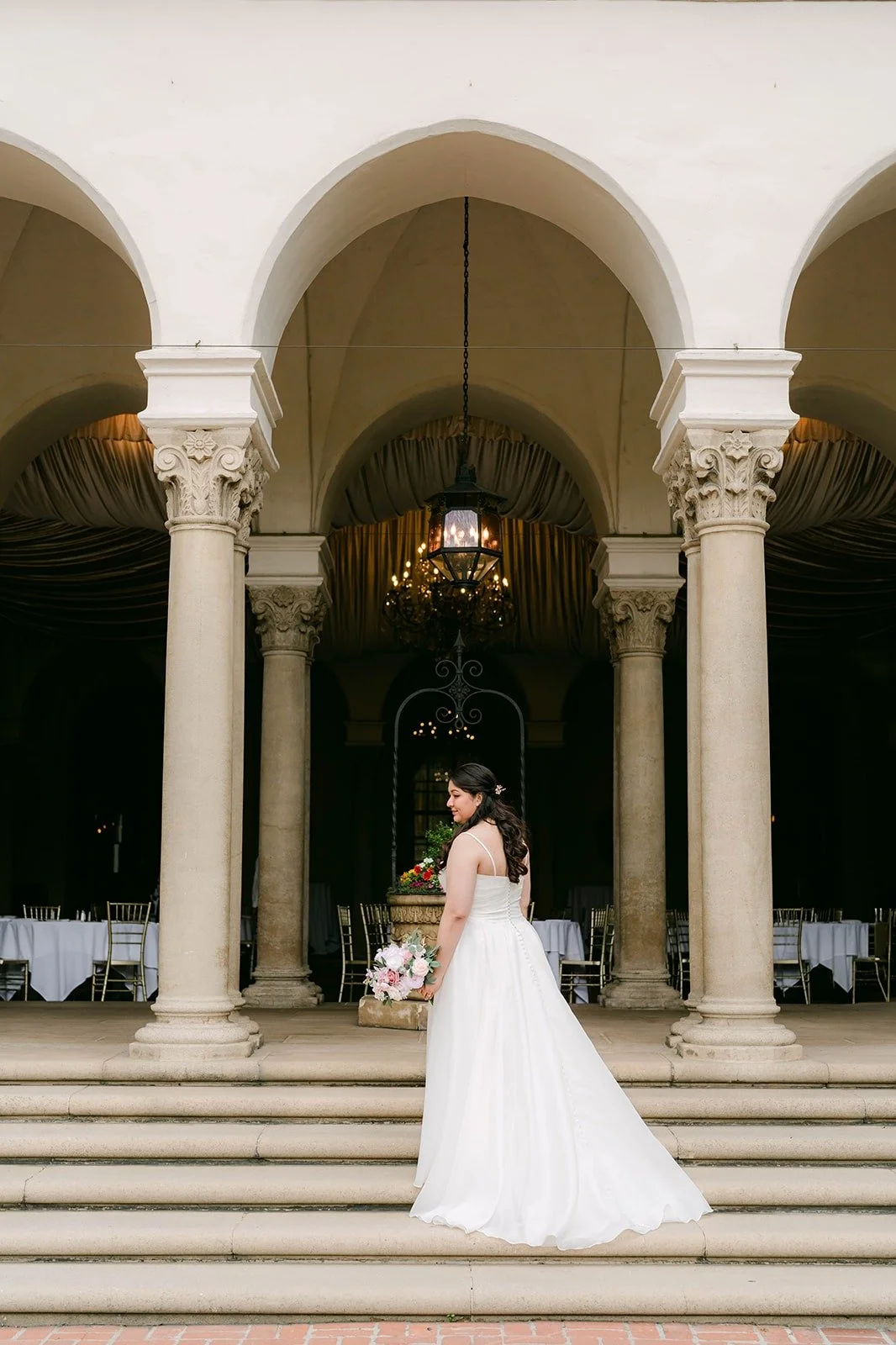 Saira on the steps below the arches and columns of The Athenaeum, photographed by One and Only Production