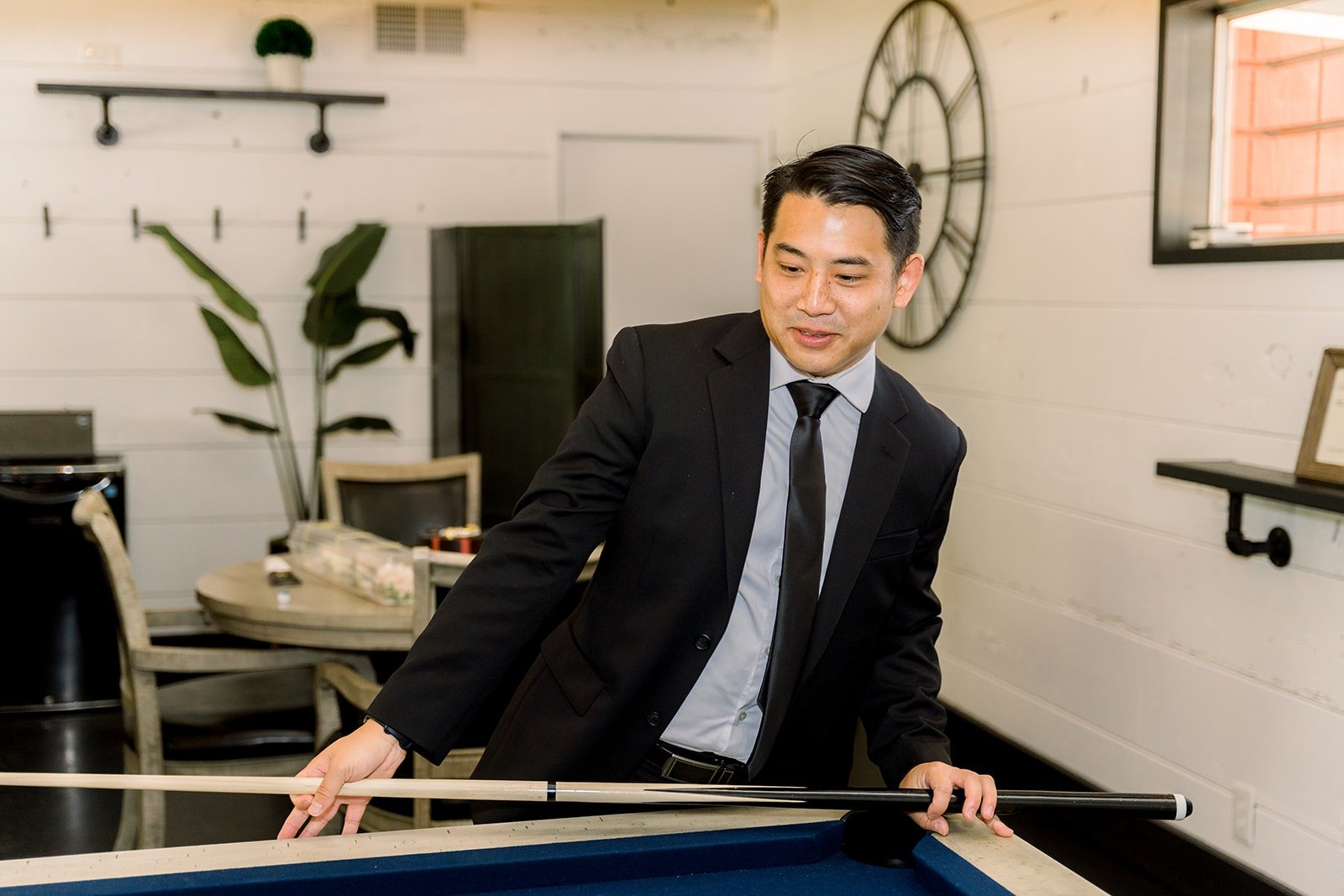 A groomsman lining up a shot at the pool table