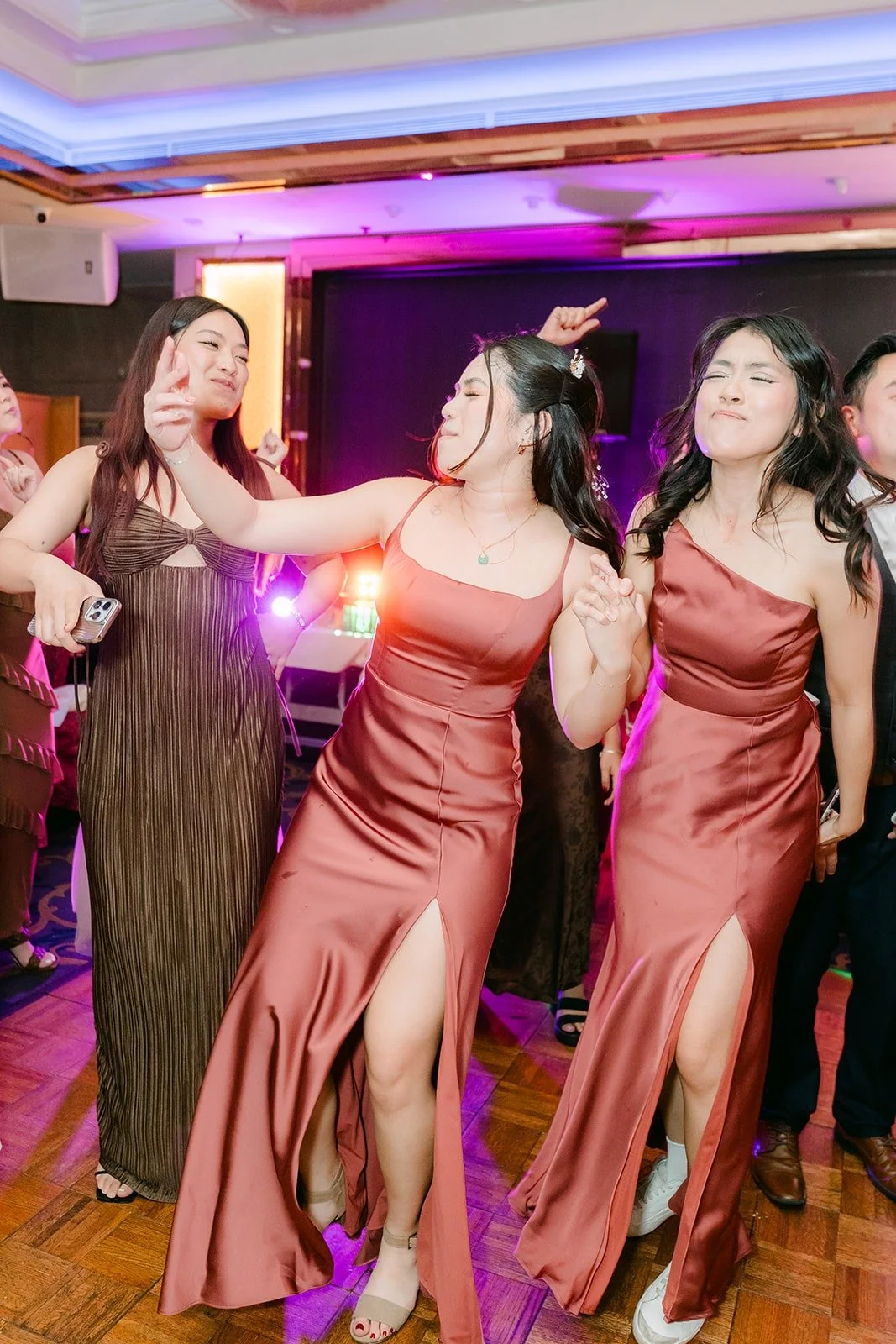 Bridesmaids in rose gowns dancing under purple lights
