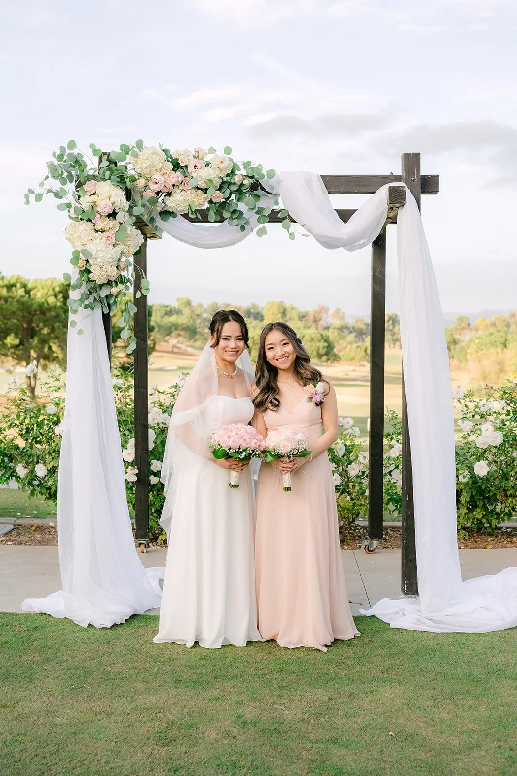Ivy with Linh and a bridesmaid at the ceremony arch