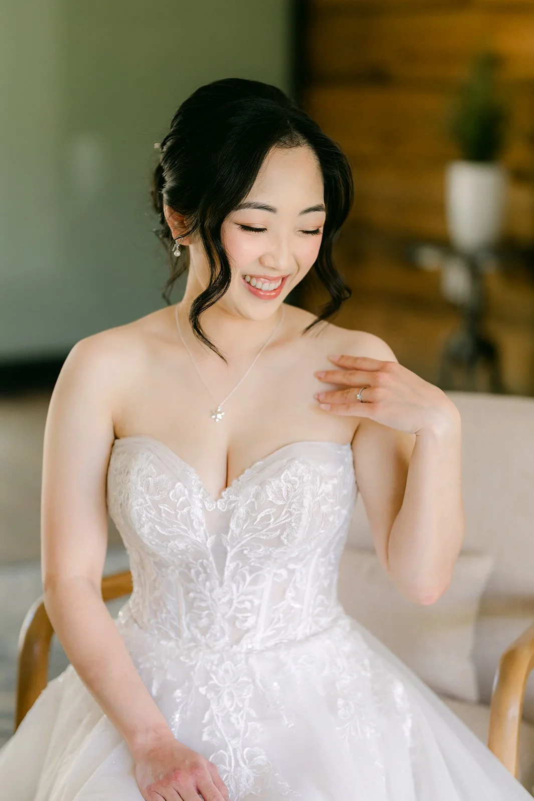 Bride adjusting her earring in a strapless lace wedding gown