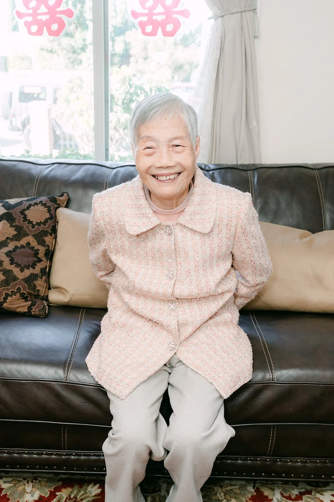 A grandmother smiling on the sofa after the tea ceremony.