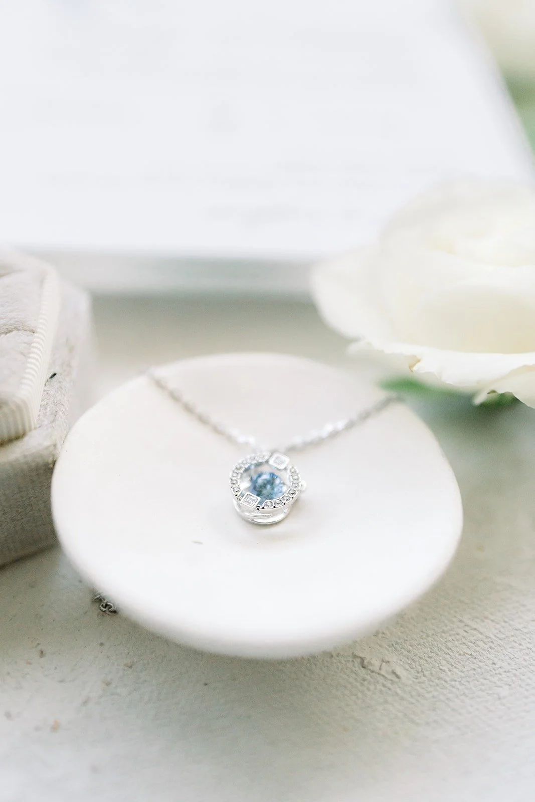 A pendant necklace resting on a small white dish