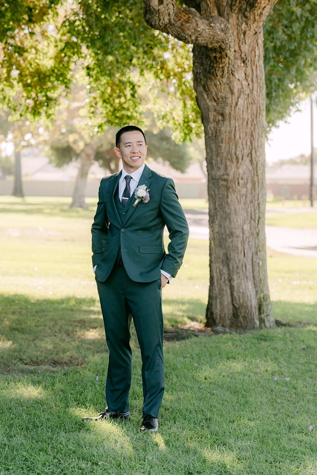 Kevin in his dark green suit under a tree at Garden Grove Park