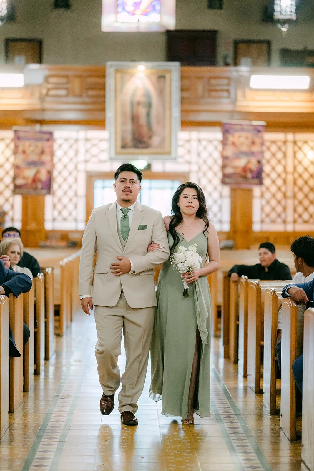 A groomsman escorting a bridesmaid down the aisle.