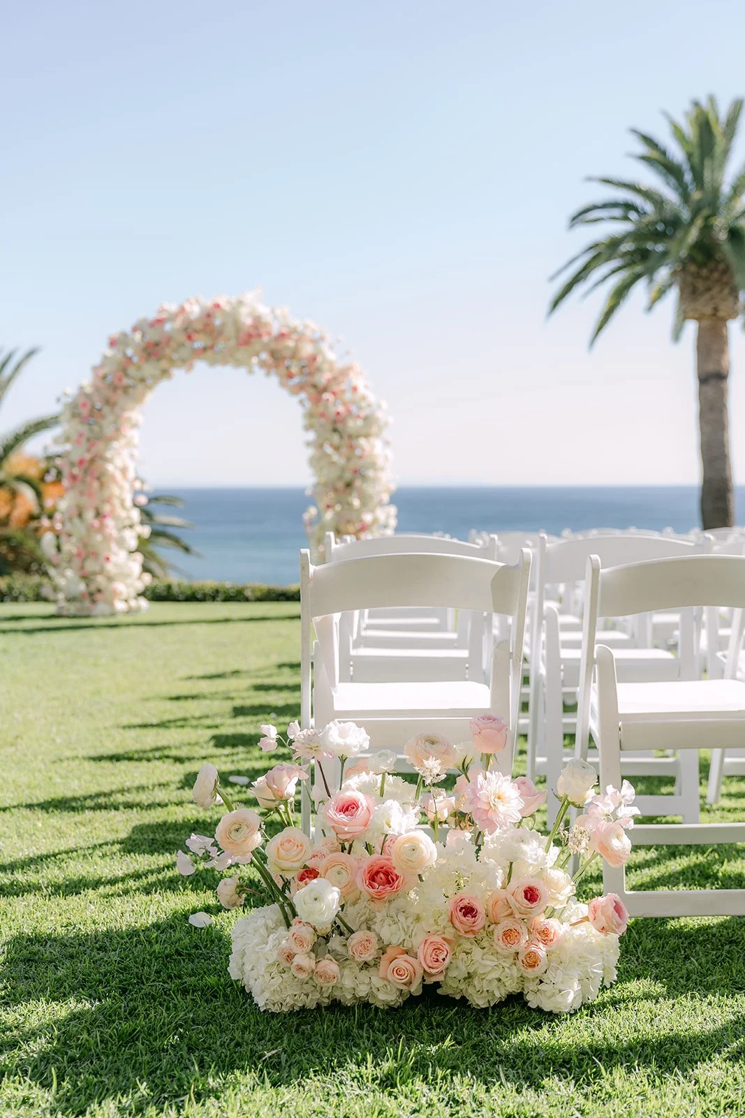 Floral aisle arrangements and white chairs on the ceremony lawn