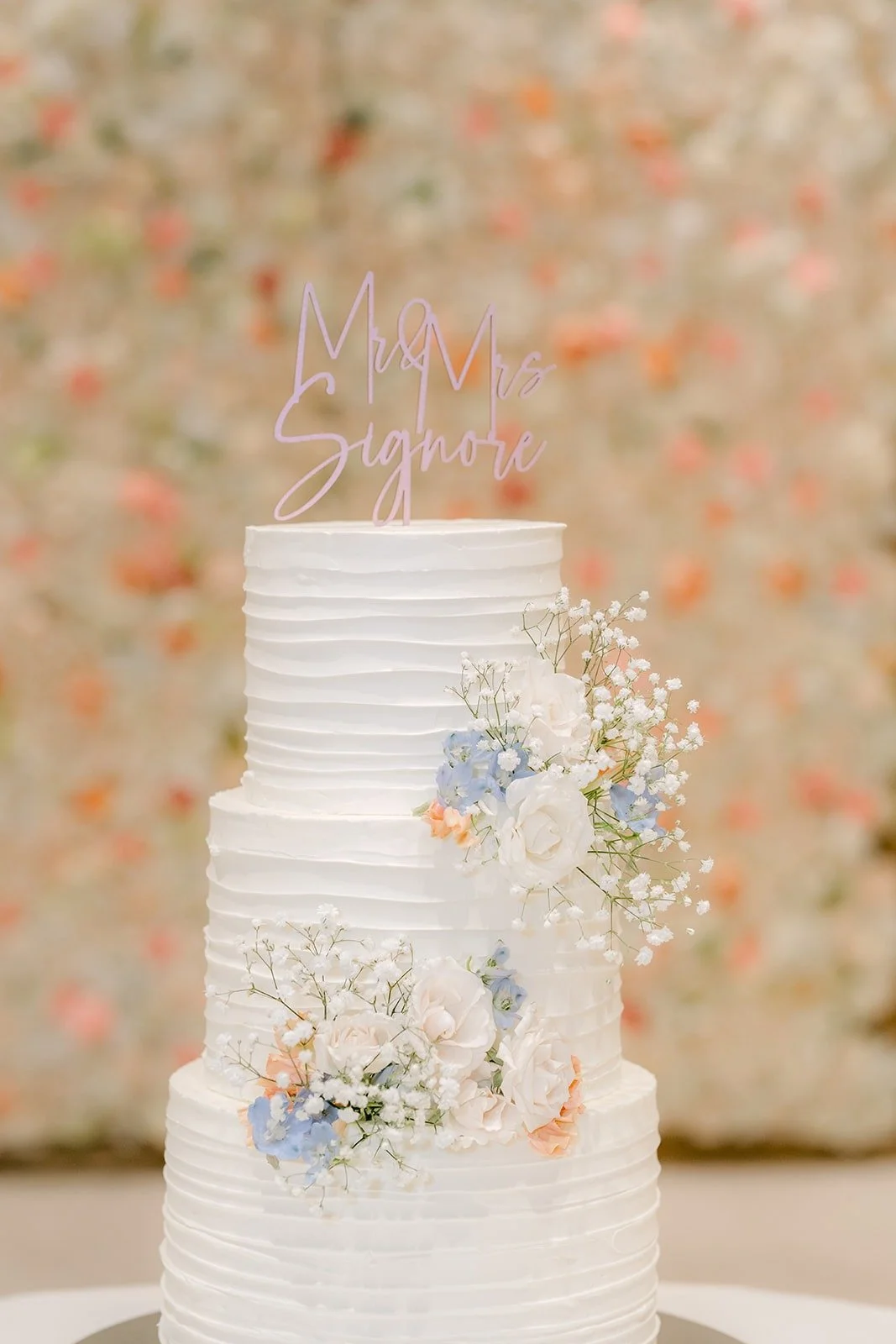 The tiered white cake decorated with blush and light blue blooms
