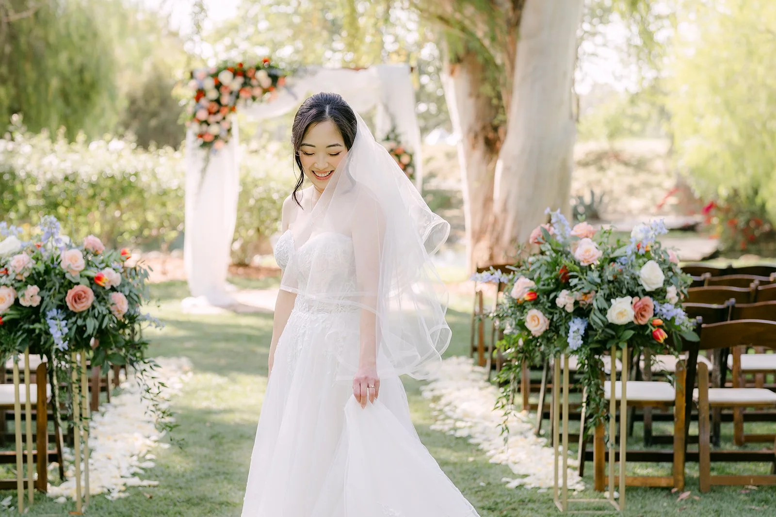 Bride standing in front of the floral ceremony arch before the guests arrive