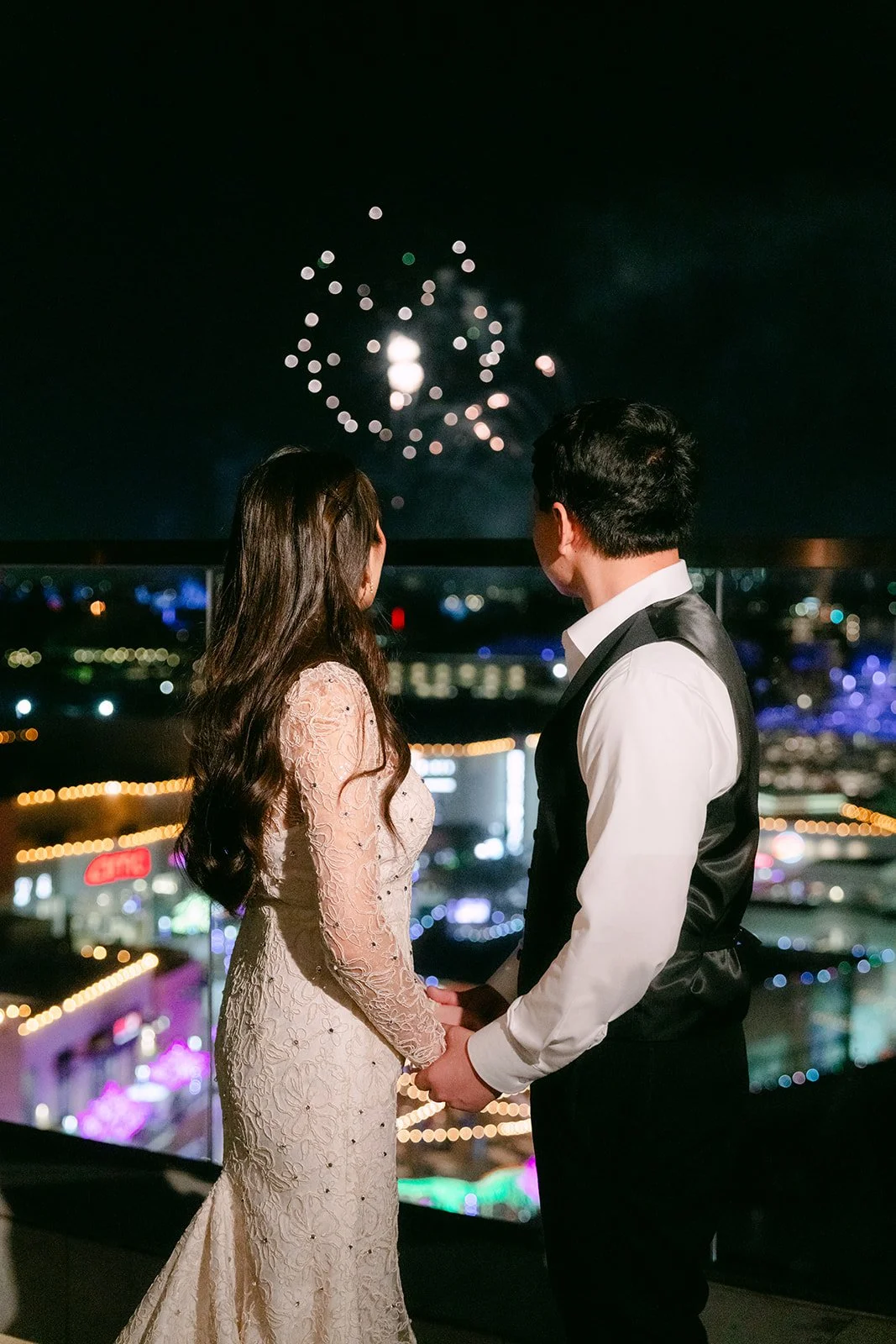 Fireworks bursting over Anaheim as the couple holds hands on the balcony