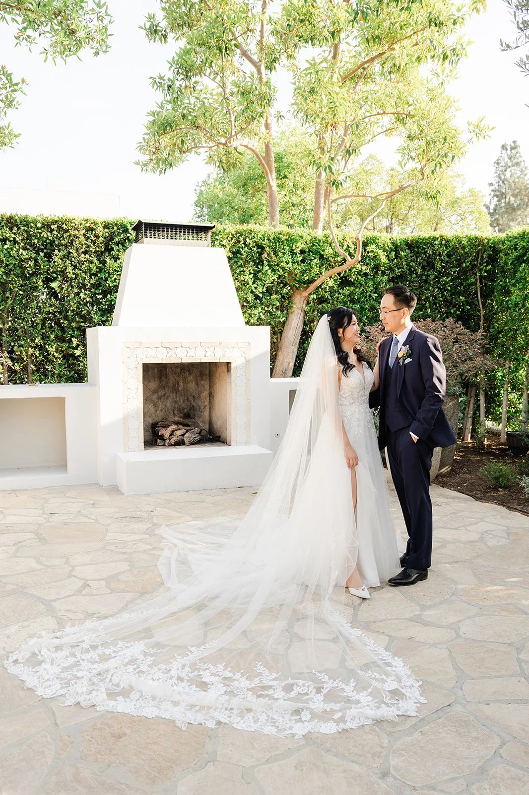 Couple by the white outdoor fireplace in the Olive Grove