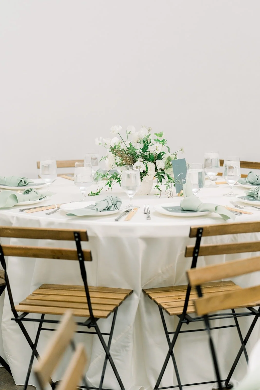 A round reception table with cafe chairs and white florals