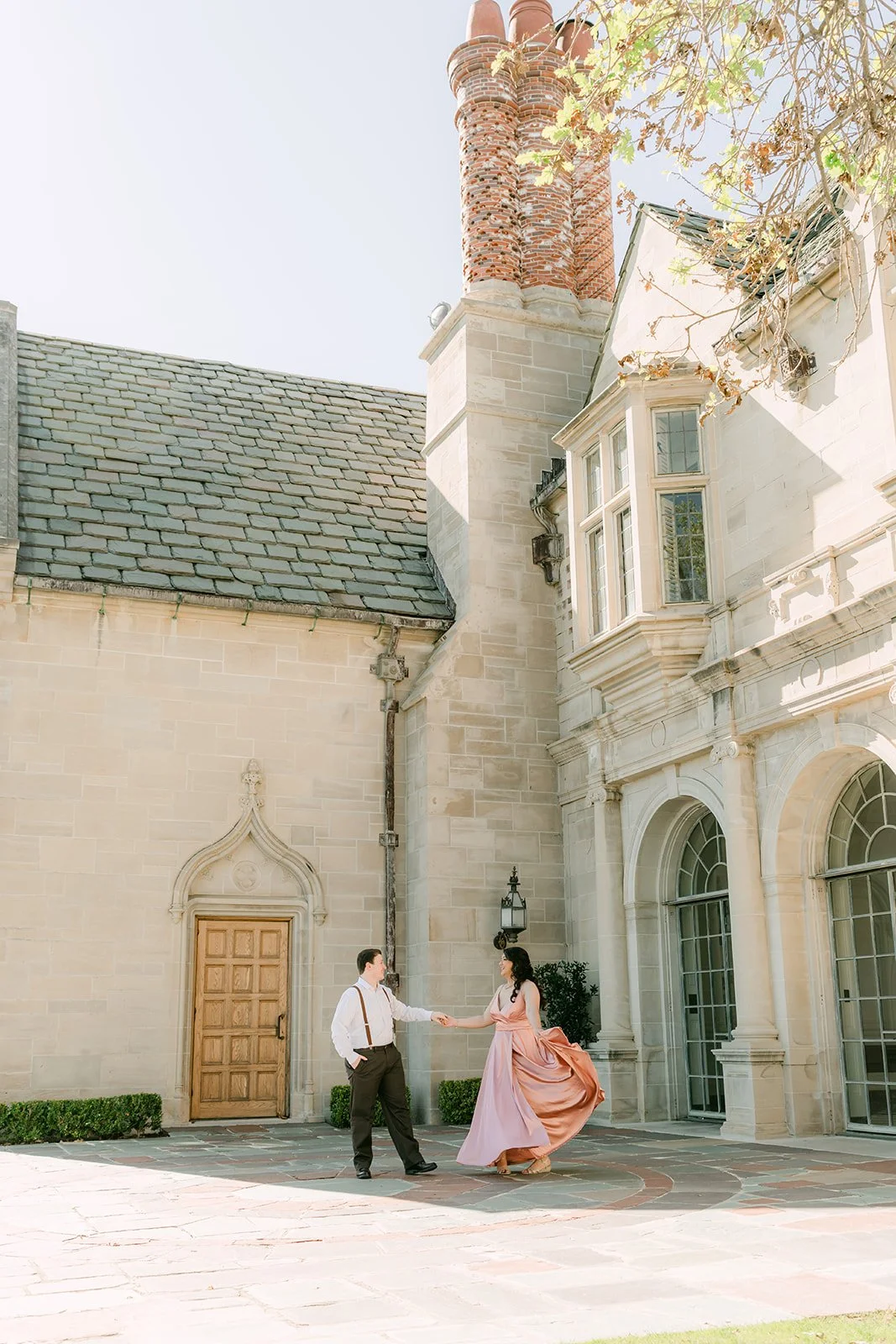 Matthew twirls Saira beside the mansion's tall brick chimney.
