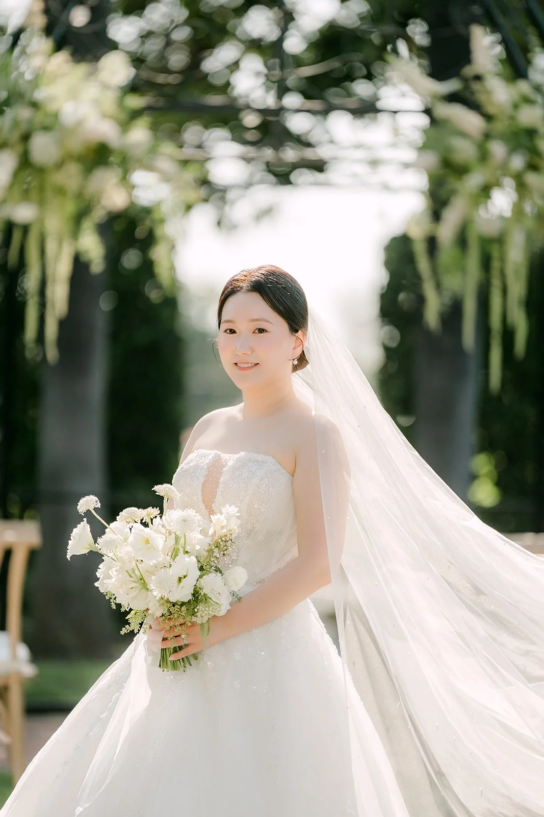 Amy with her bouquet under the trees in the garden
