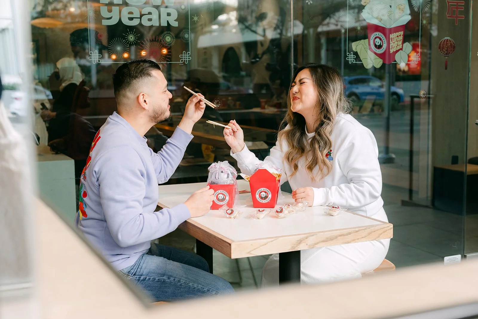 Linh and Ankush sharing their meal at a table by the window.