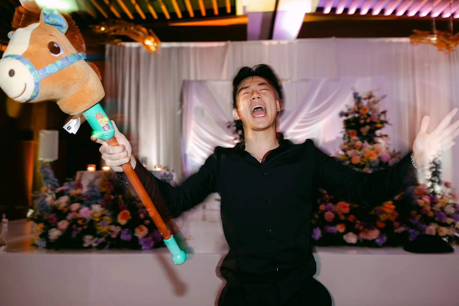 Groomsman cheering with a stick horse during the cowboy hat toss