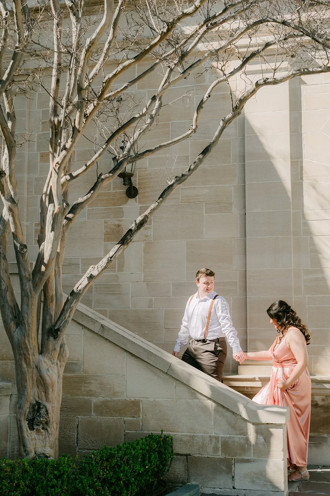 Saira and Matthew on a limestone staircase beneath a bare tree beside Greystone Mansion.