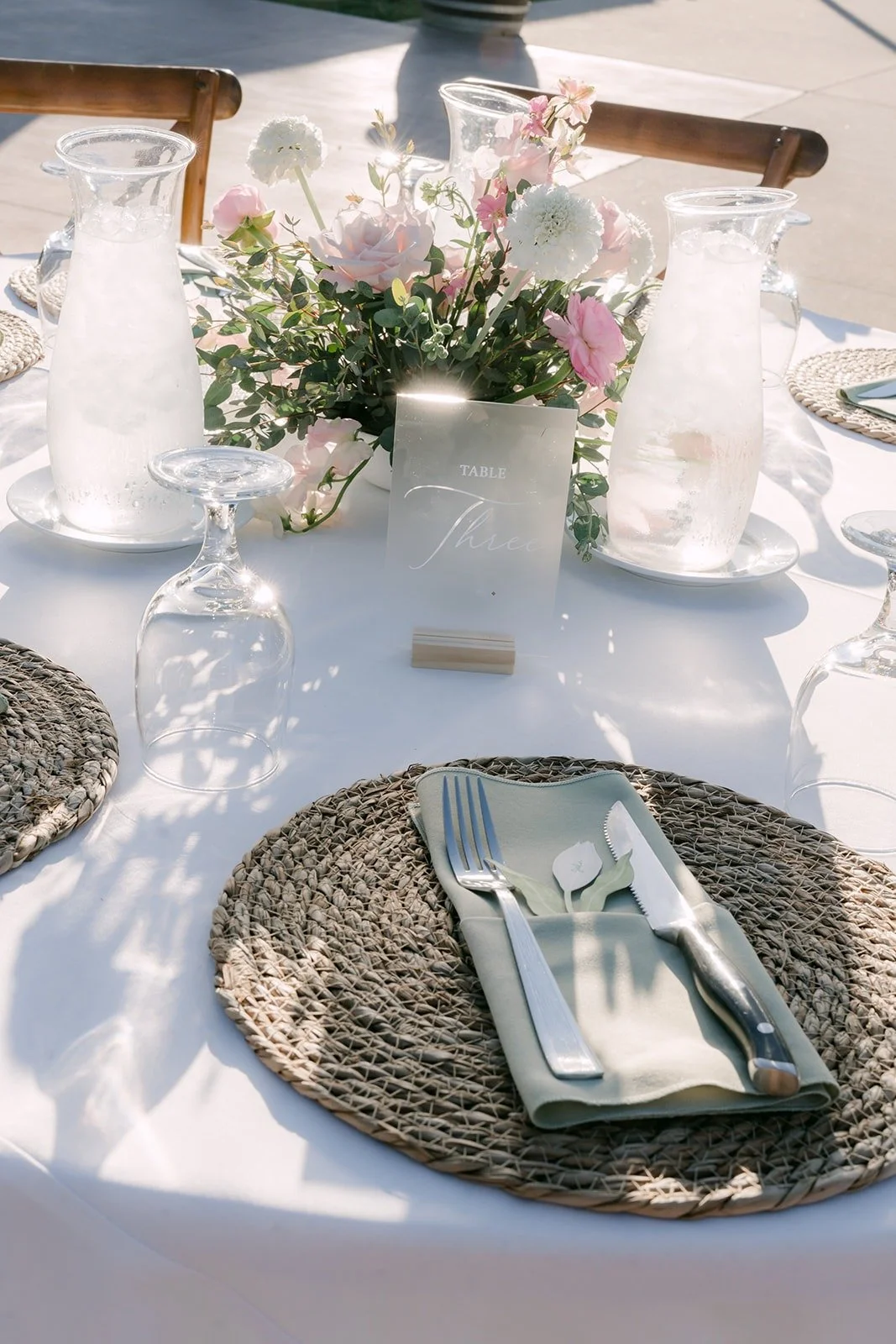 Rattan chargers, green napkins and blush florals on the reception tables