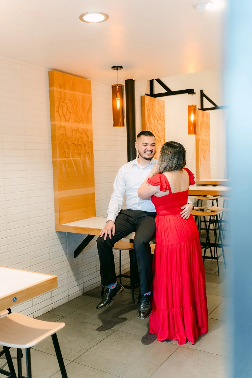Linh hugs Ankush as he sits on a stool inside the restaurant, photographed by One and Only Production.