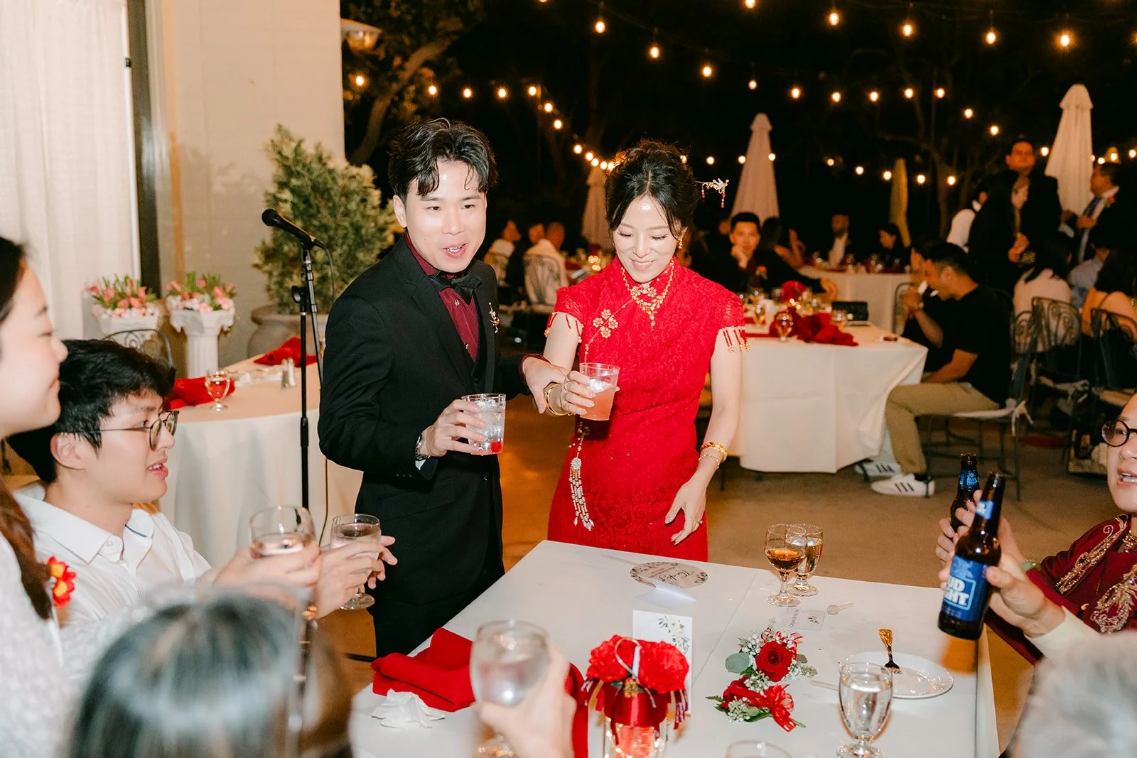 Elaine and Wen raising their glasses with guests during table toasts.