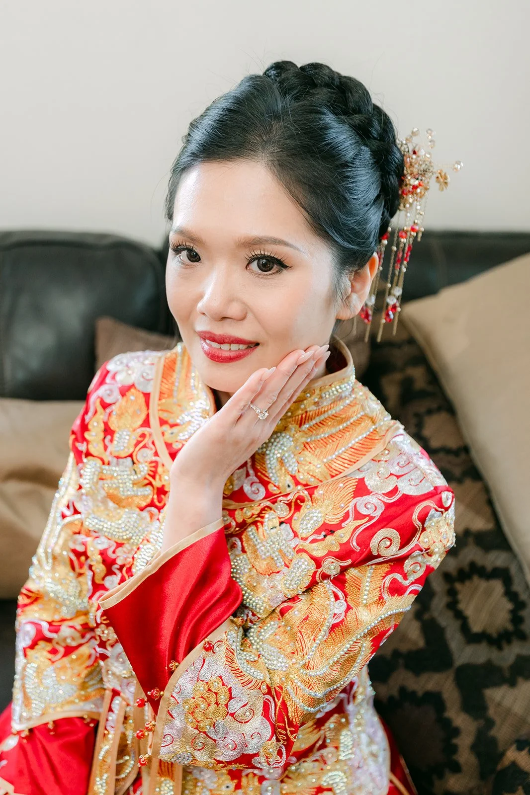 Close portrait of a bride in her qun kwa touching her earring.