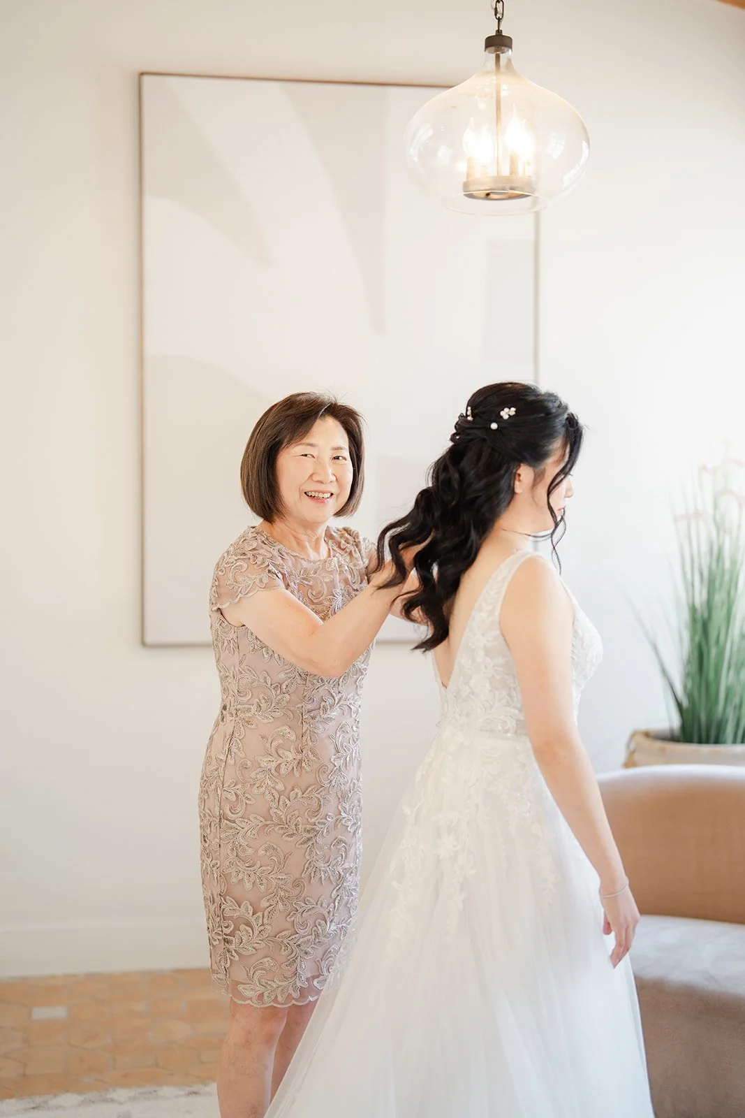 Constance's mom fastening the back of her wedding gown