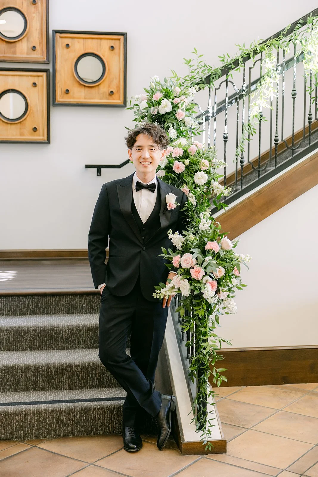 Tony leaning on the floral staircase railing before the first look