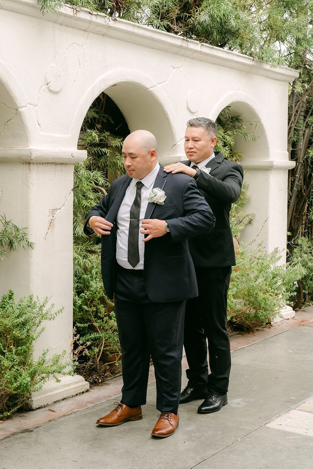 A groomsman helping Yao with his jacket