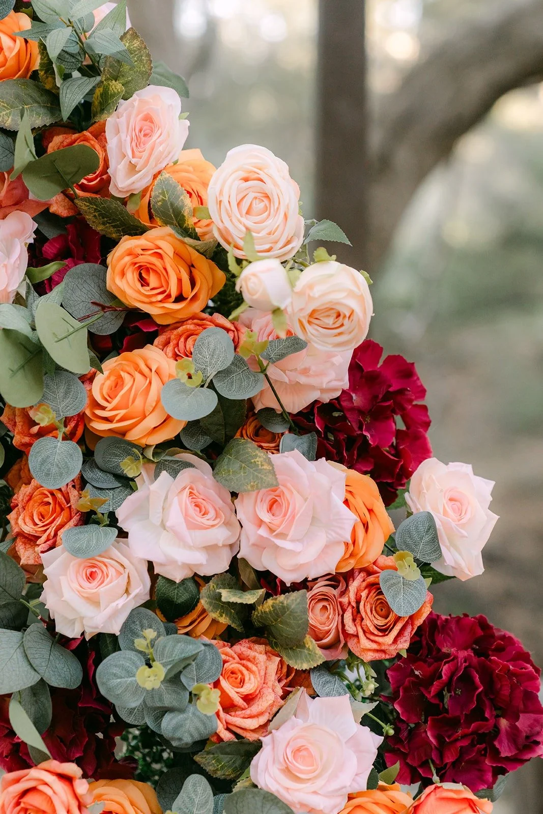 Close up of peach, pink, orange and burgundy roses on the ceremony arch
