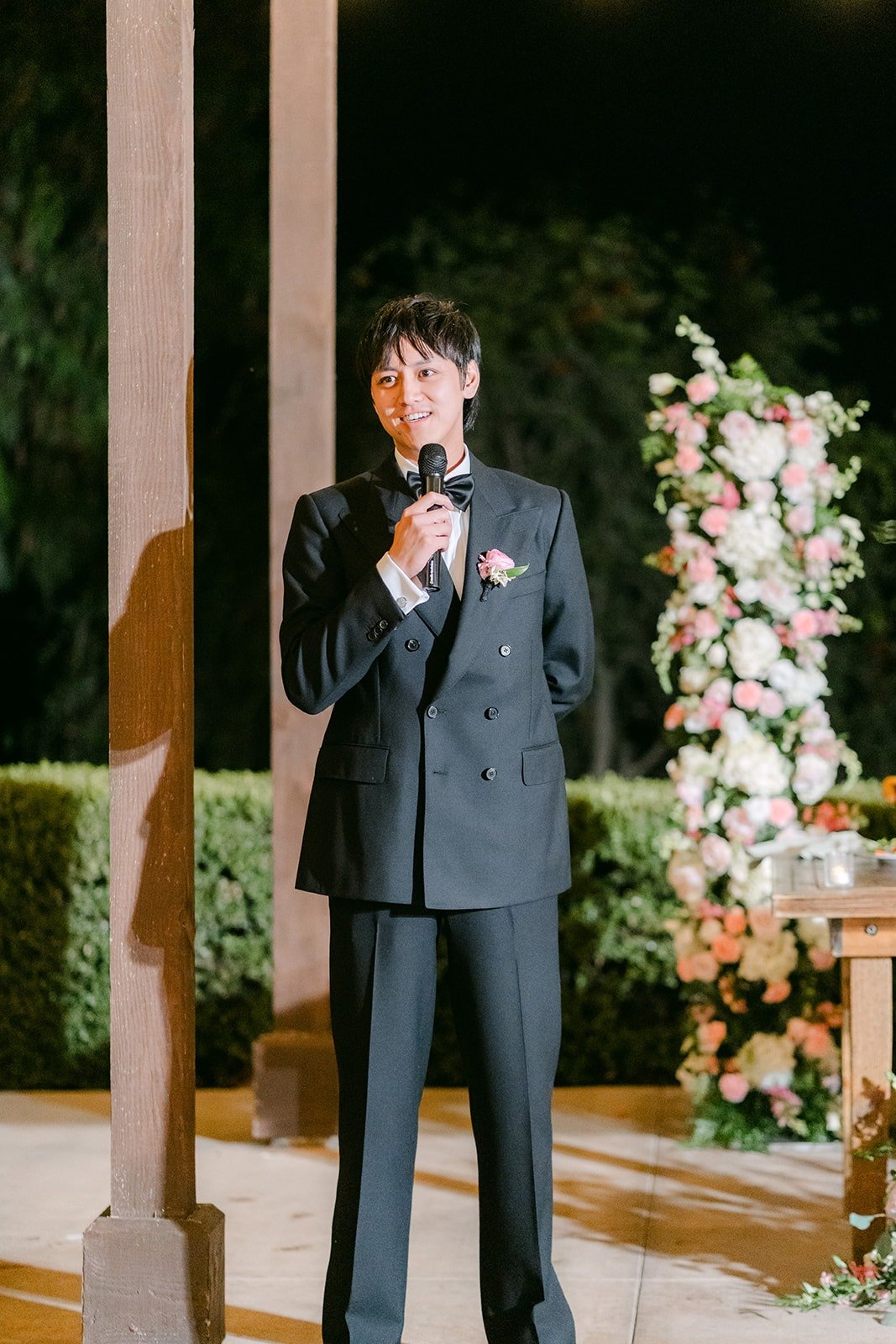 A groomsman giving a speech beside the sweetheart table