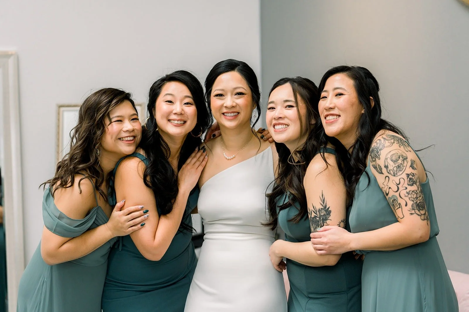 Bridesmaids in sage green crowd around Cindy