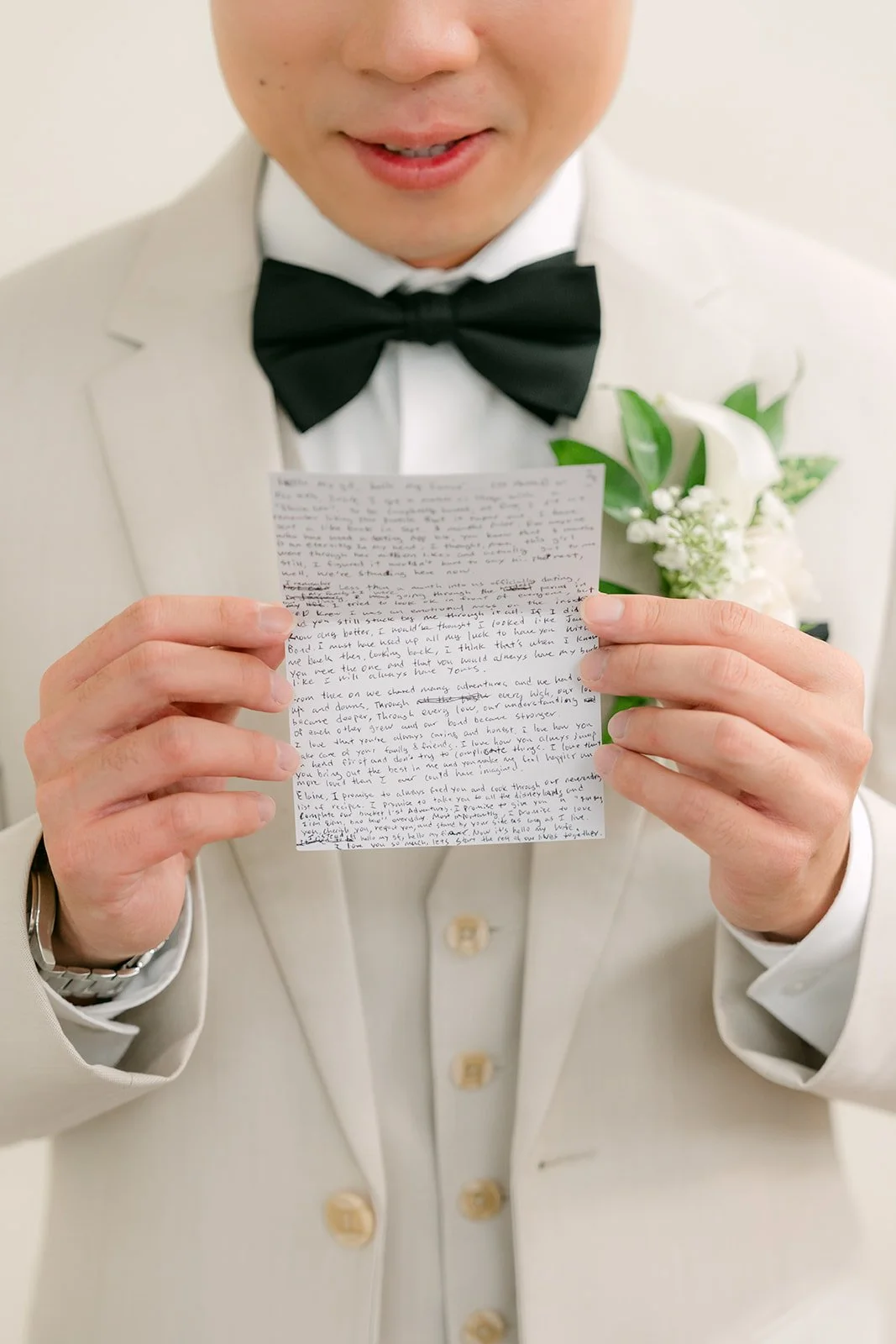 Wen holding his vow book in his cream tuxedo.