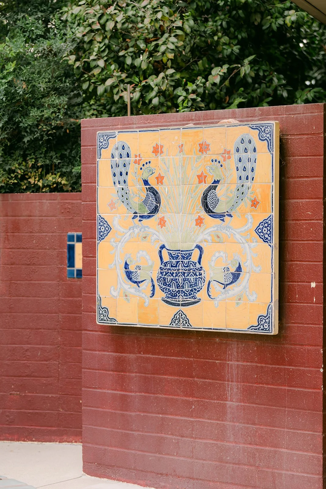 Peacock tile mural on a brick wall at the LA County Arboretum.
