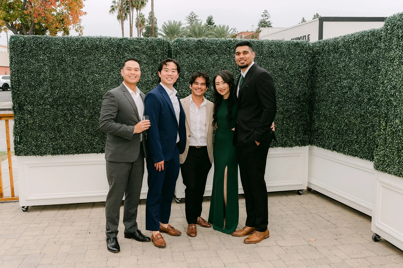 Guests posing in front of the green hedge wall on the patio.