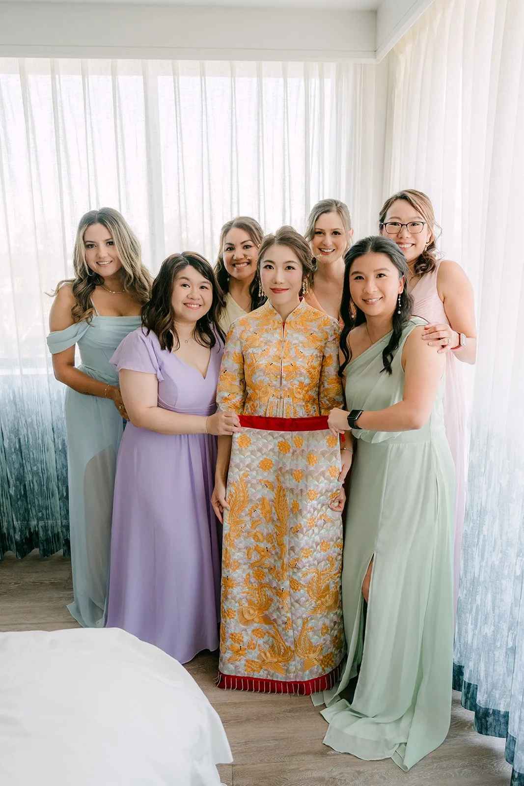Christie stands with her bridesmaids in pastel dresses in the hotel suite.