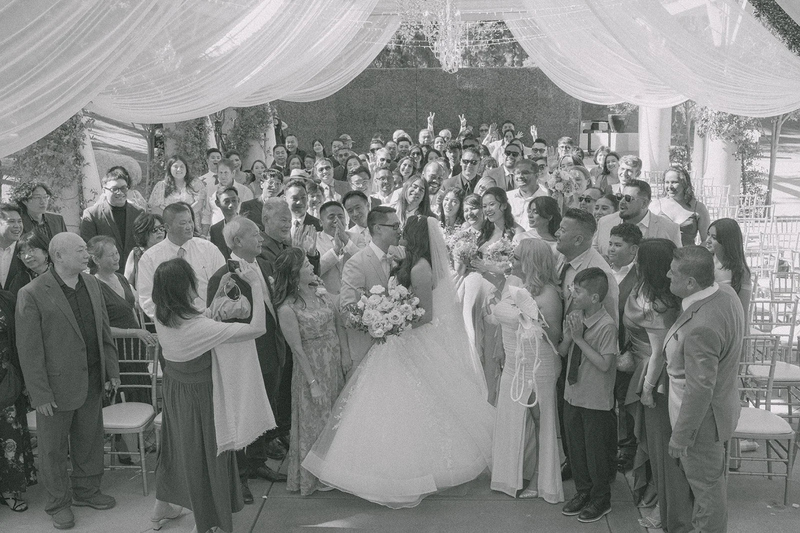 Black and white group photo of every guest with Sandra and Kevin under the pergola, photographed by One and Only Production.