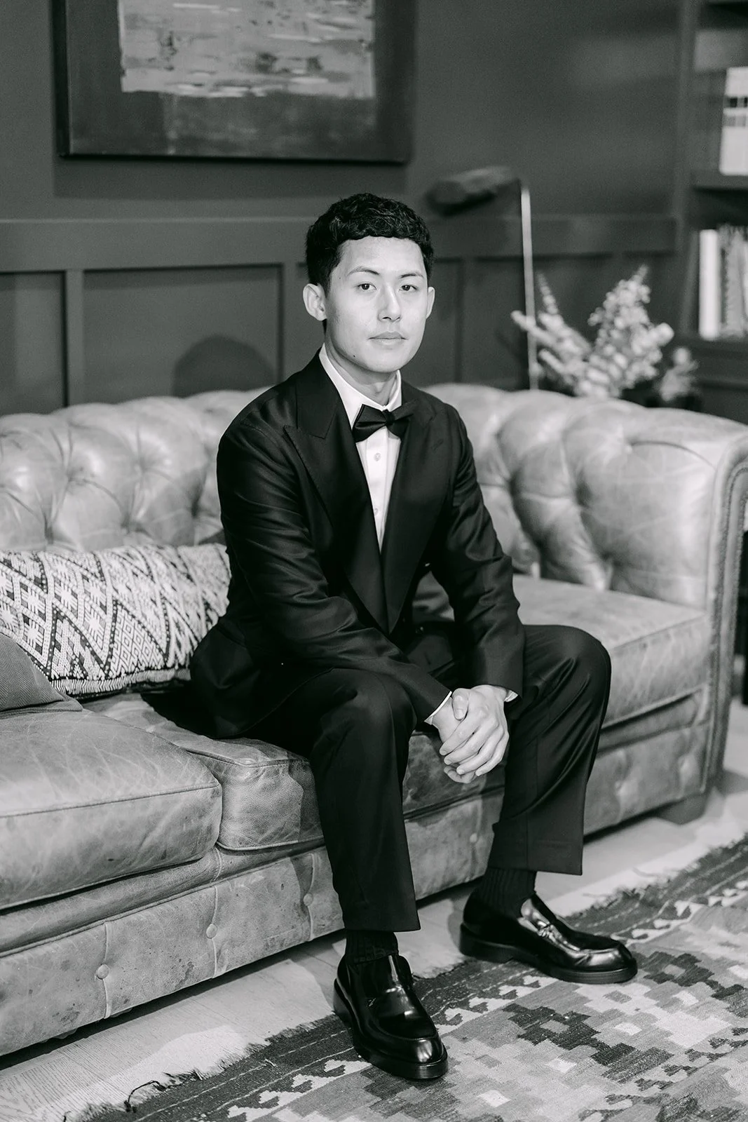 Black and white portrait of Richard on a tufted sofa in the library suite