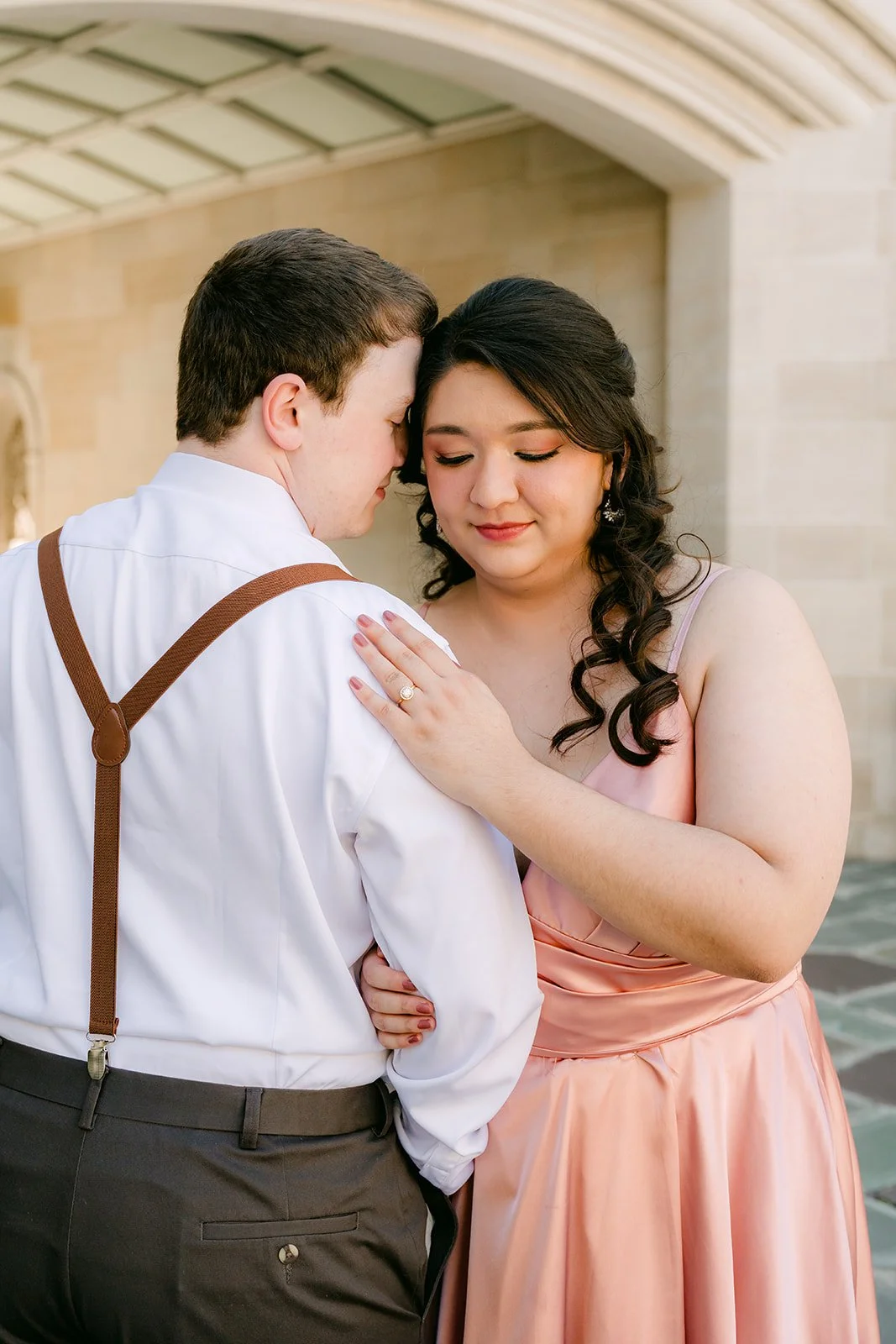 Matthew and Saira embracing beneath the stone archway at Greystone Mansion.