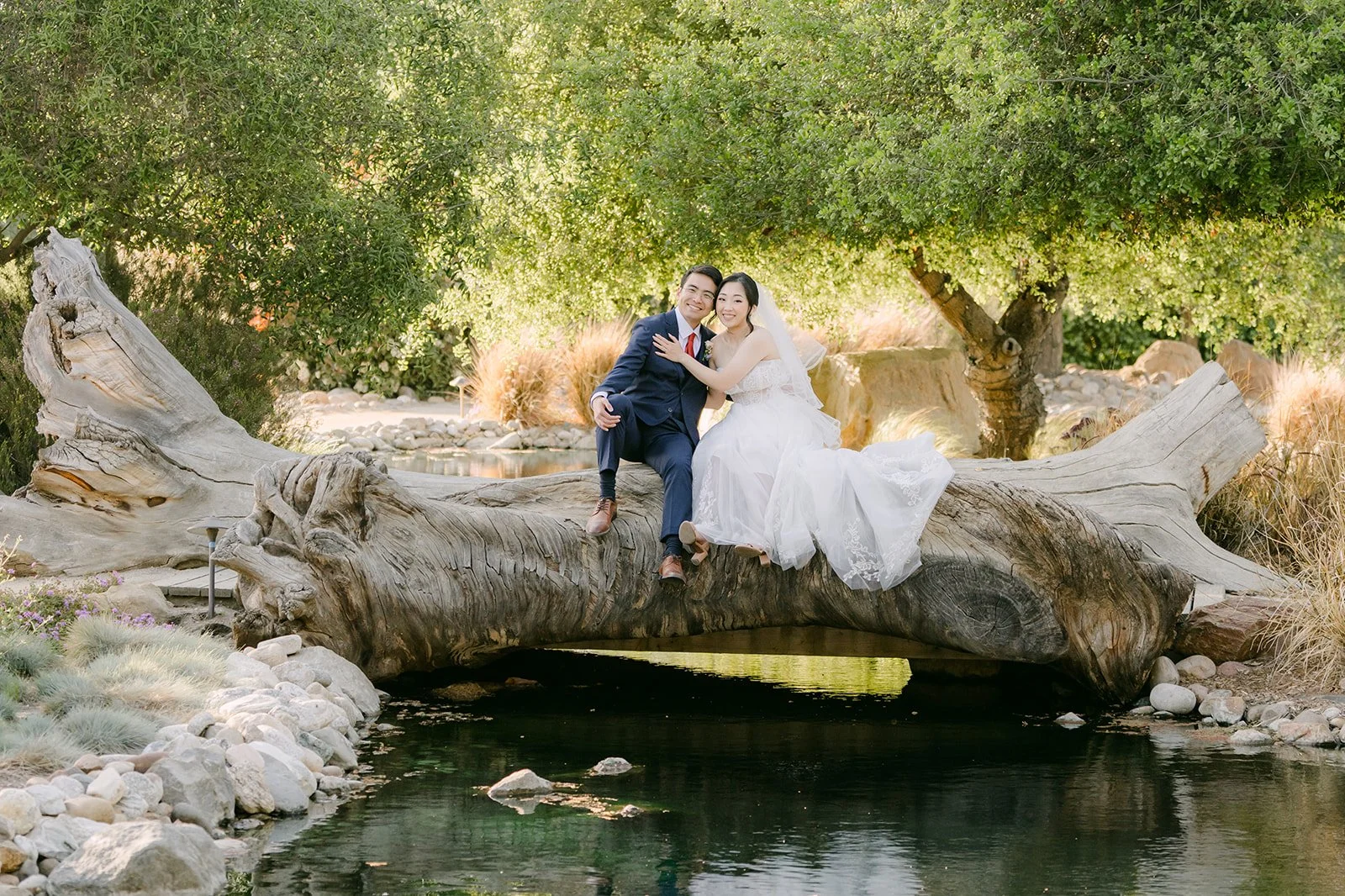 Couple seated on a rock beside the pond and waterfall