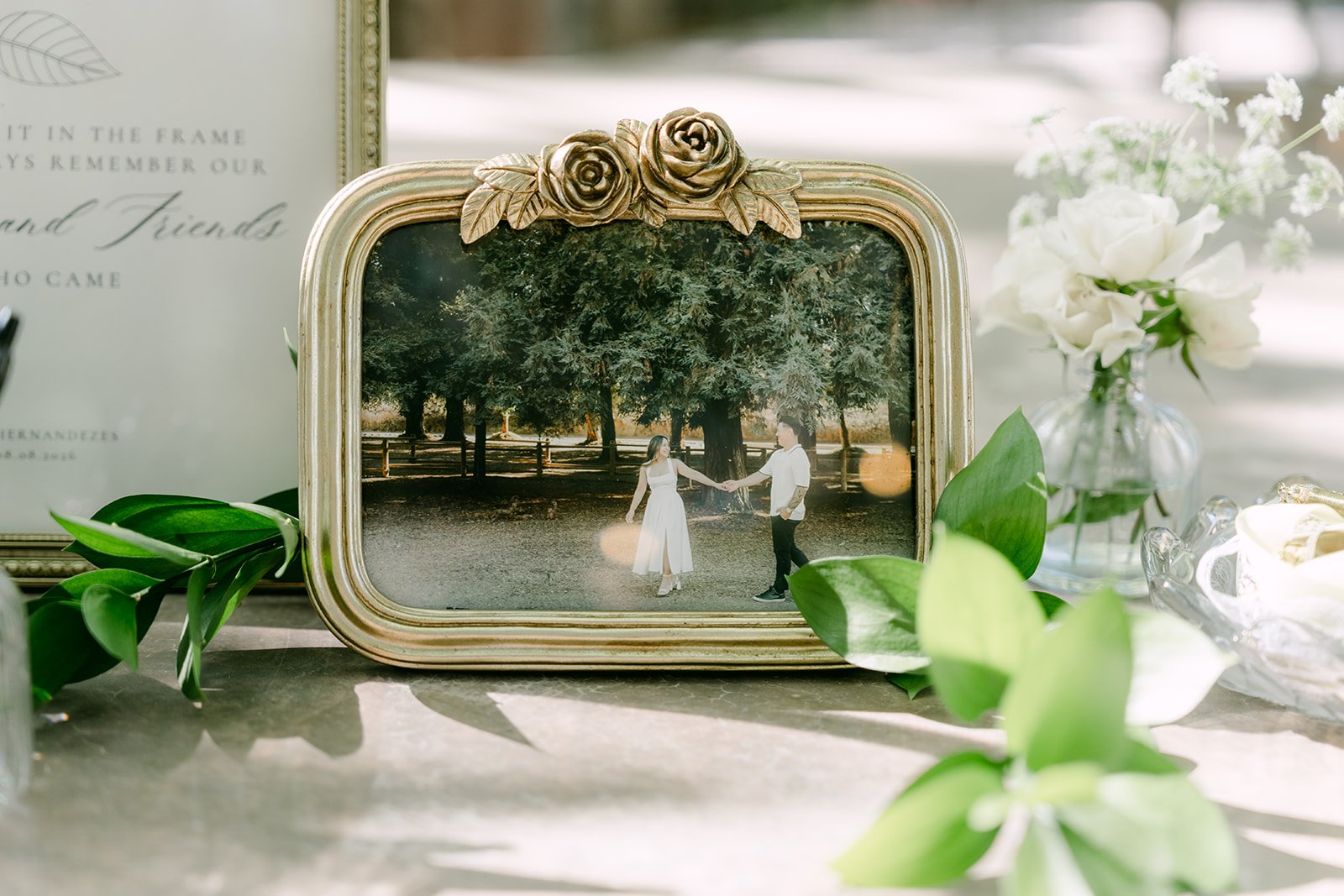 Nicole and Caryl reflected in a gold mirror beside their ceremony stationery.