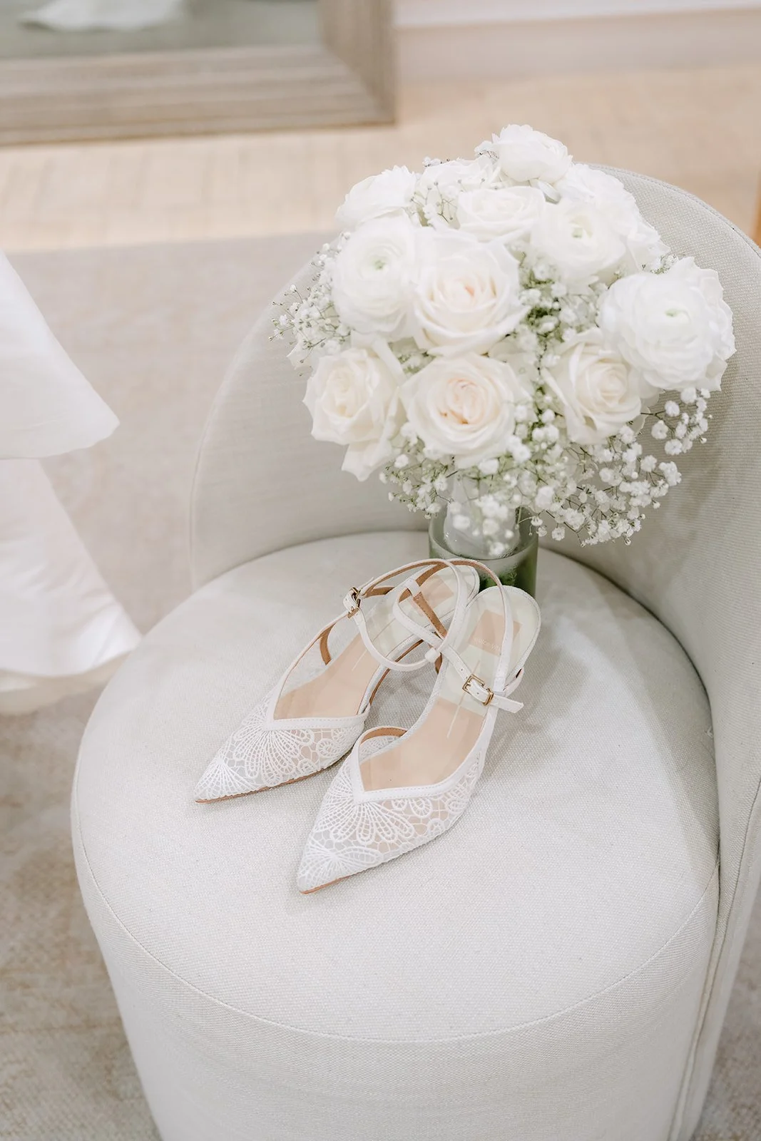 White rose bouquet and embellished bridal heels on a round white ottoman