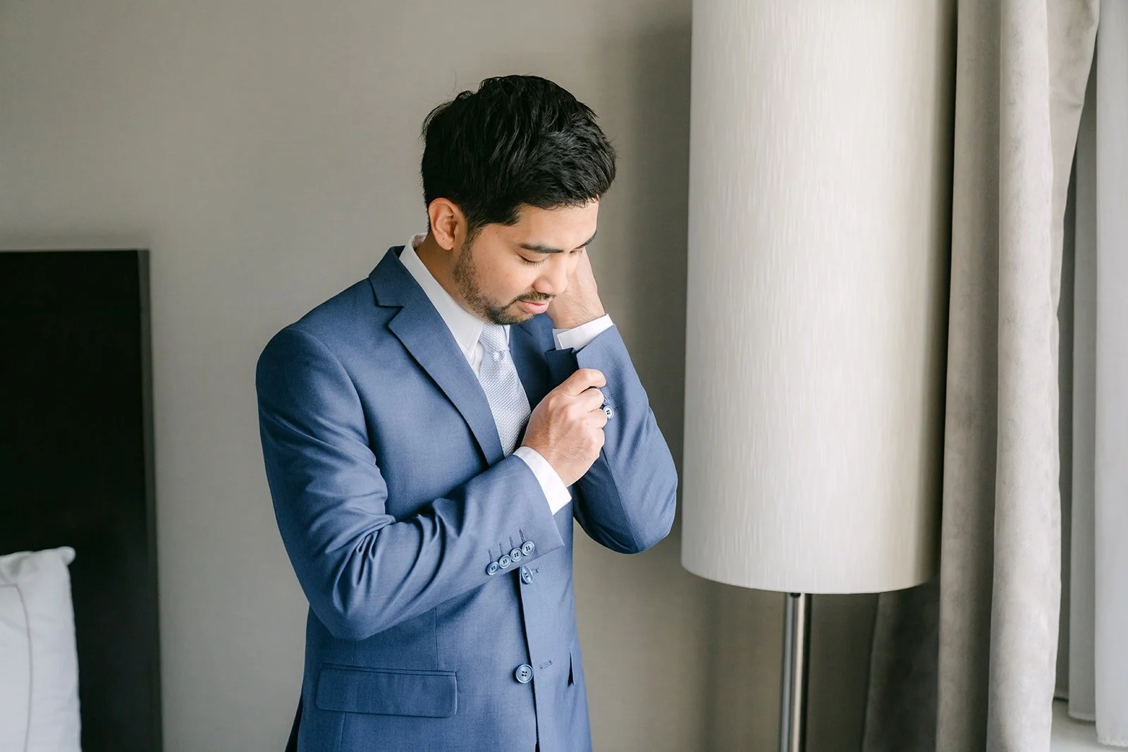 Mark in his blue suit adjusting his boutonniere