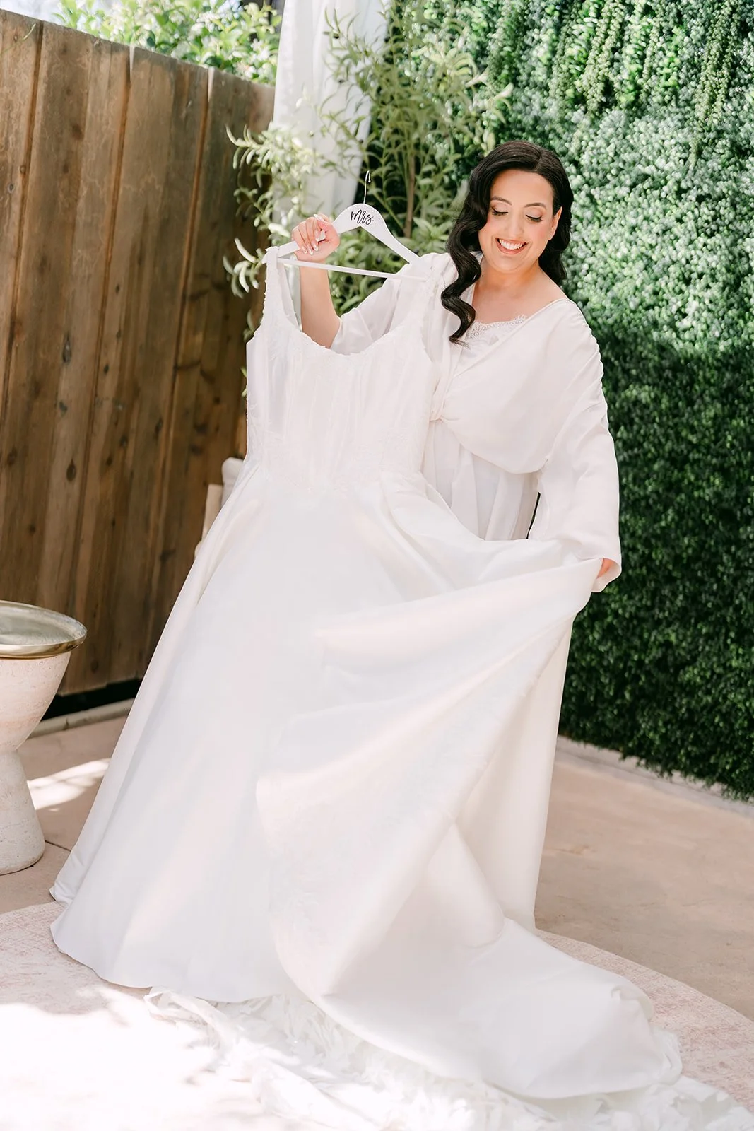 Bride in a robe holding up her wedding gown in the getting ready suite